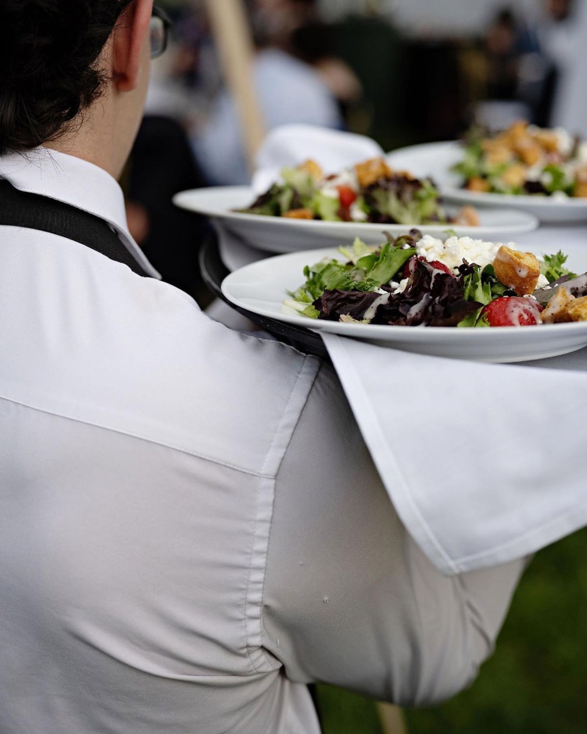 Kellner serviert frische Salatteller mit Beeren, Feta und Croutons