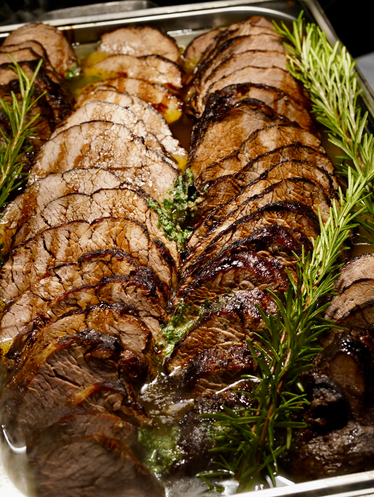 Frisch aufgeschnittener Rinderbraten mit Rosmarin und Bratensaft am Cateringbuffet