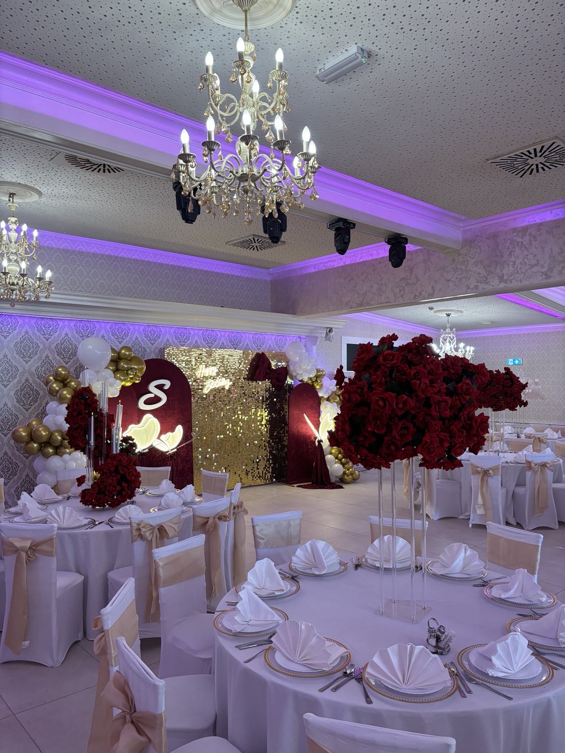 Glamouröse Geburtstagsdekoration in Rot und Gold mit Pailletten-Wand, Rosenarrangements und beleuchtetem Initial
