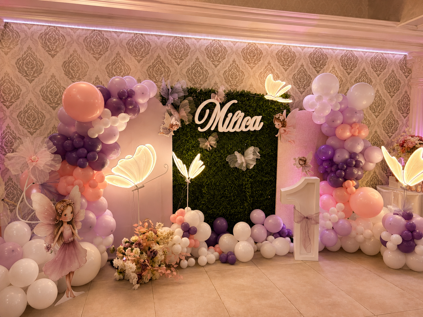 Märchenhafte erste Geburtstagsfeier mit Feen-Motiv, lila-rosa-weißer Ballongirlande, beleuchteten Schmetterlingen und Namensschriftzug