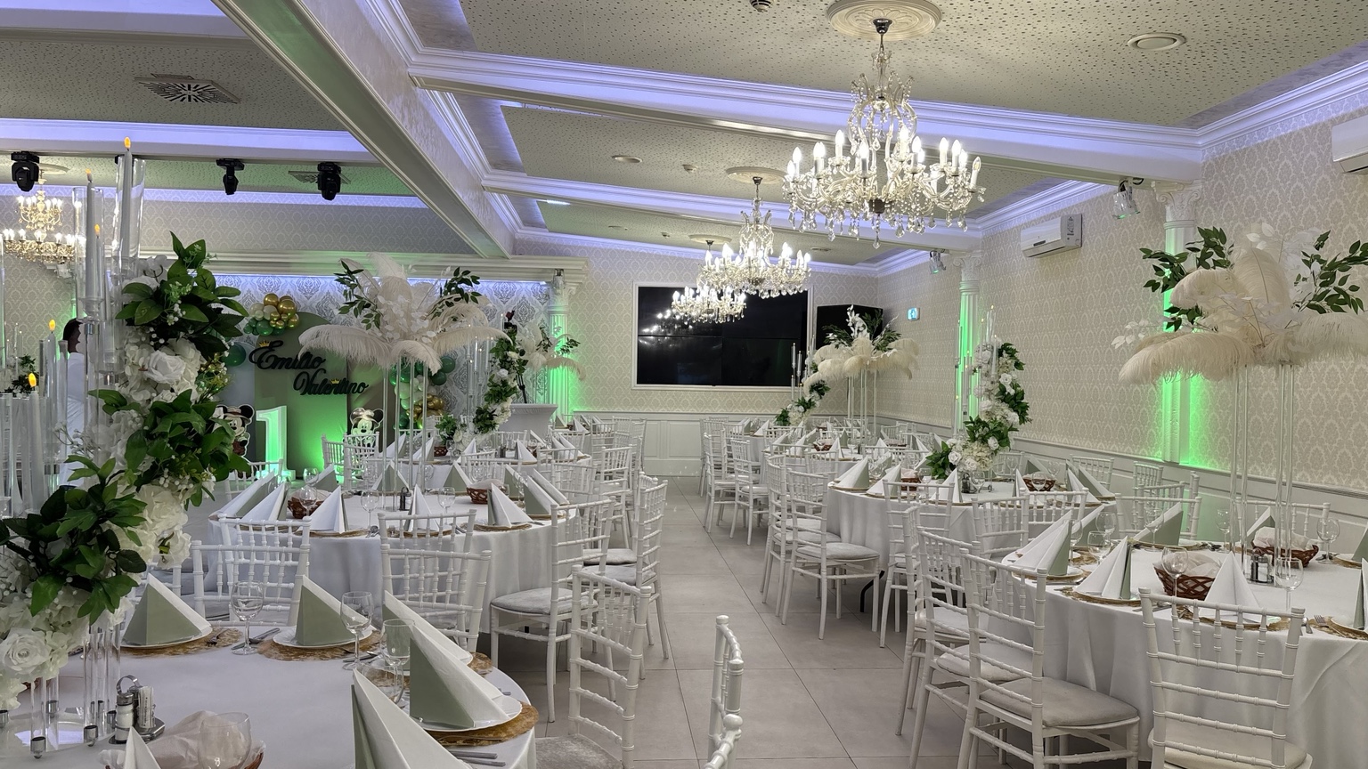 Festsaal in Grün und Weiß mit Chiavari-Stühlen, hohen Federn- und Blumenarrangements