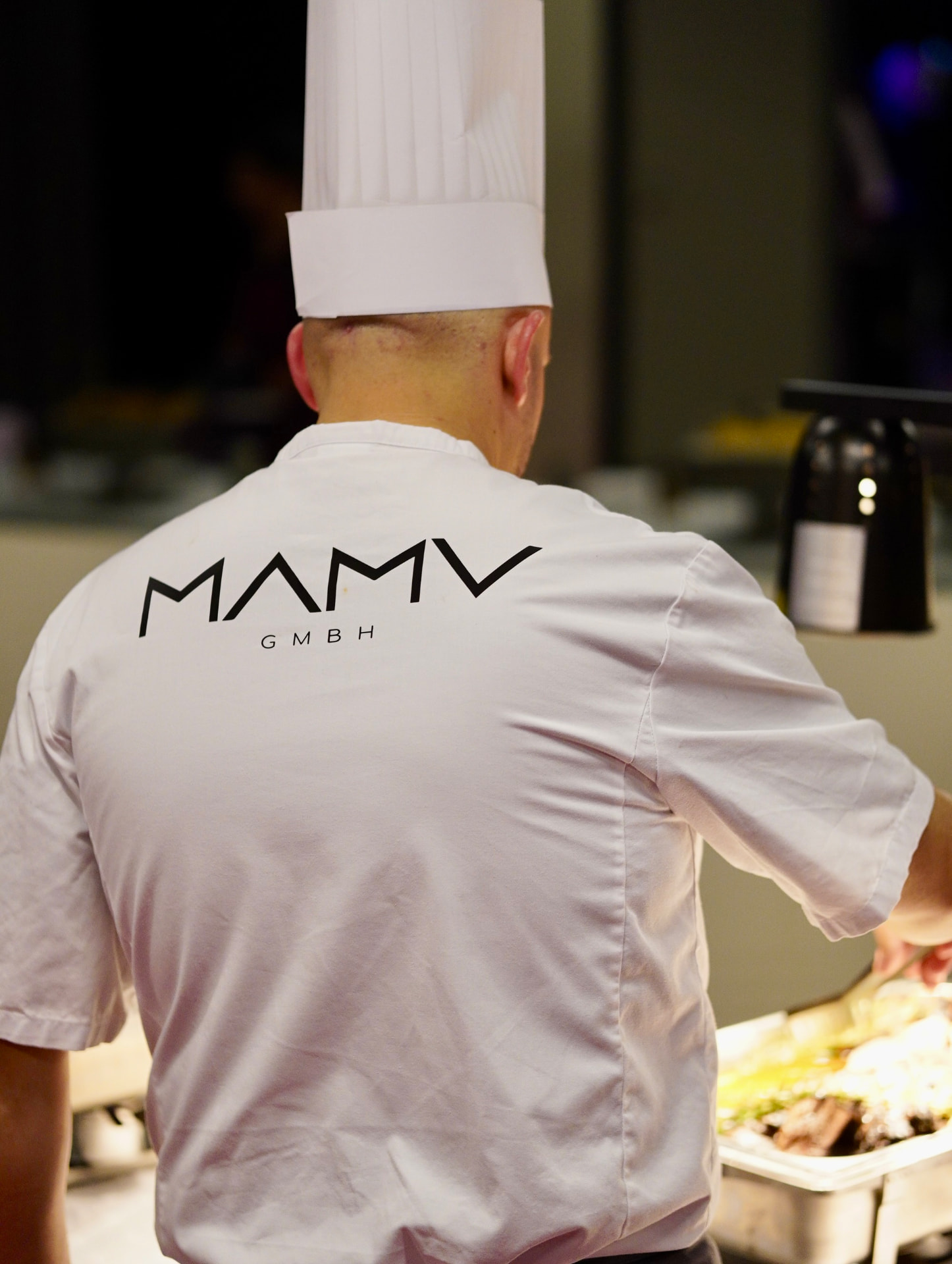 Küchenchef bei der sorgfältigen Ausgabe frisch zubereiteter Speisen
