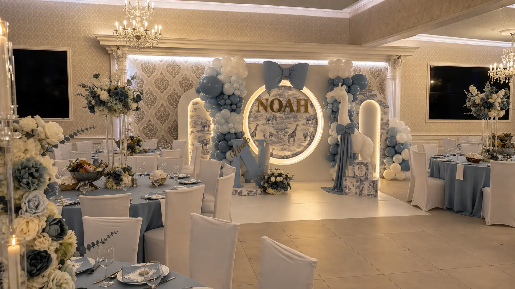 Festsaal in Blau und Creme mit beleuchteter Safari-Rundwand, Ballongirlanden und hohen Blumenarrangements