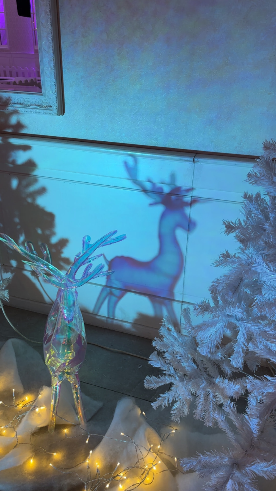 Winterliche Deko-Detail mit beleuchtetem Rentier, weißem Tannenbaum und Lichterkette