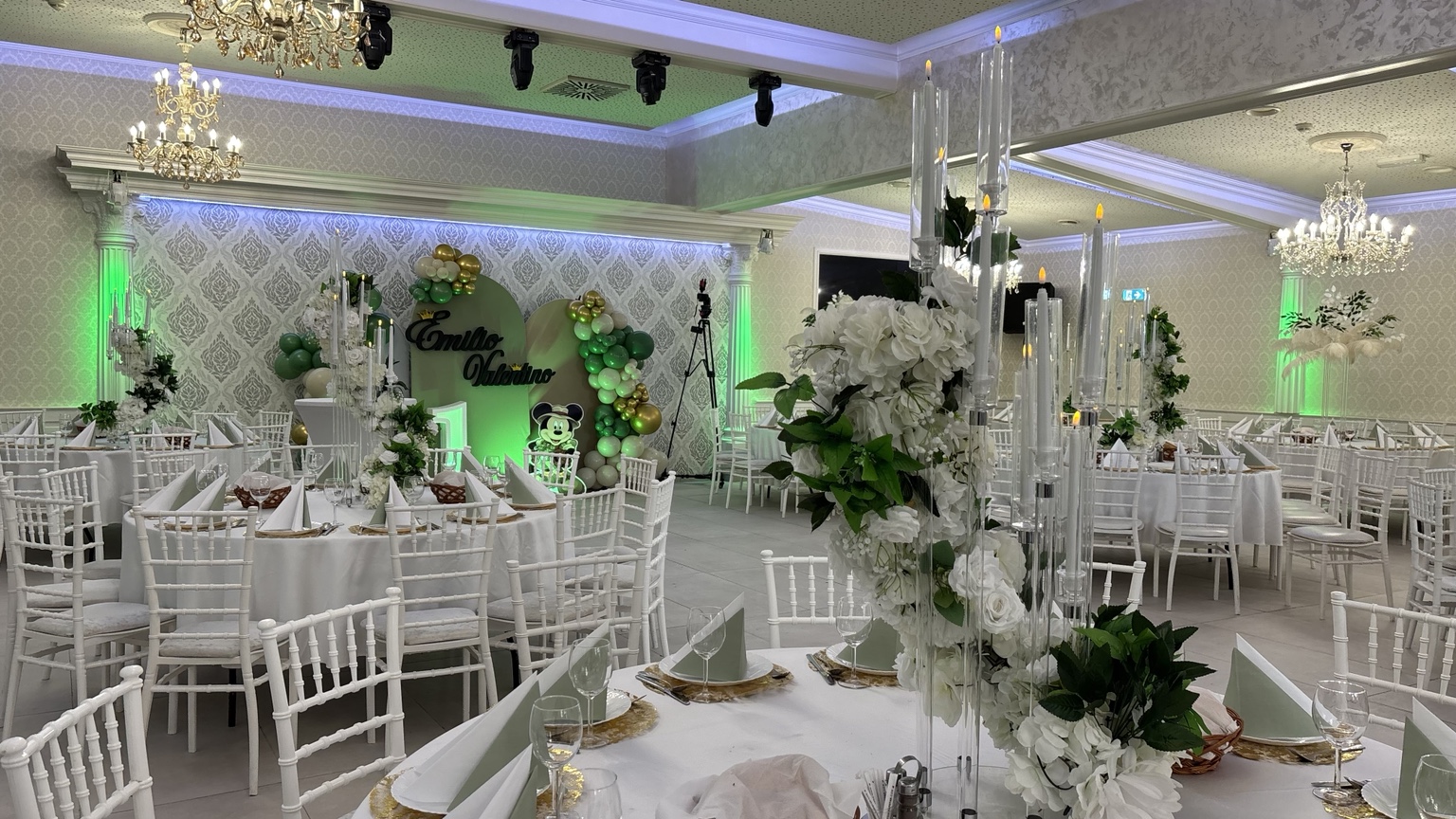Festsaal in Grün und Weiß mit gedeckten Tischen, grüner Ballon- und Blumendekoration sowie Kronleuchtern
