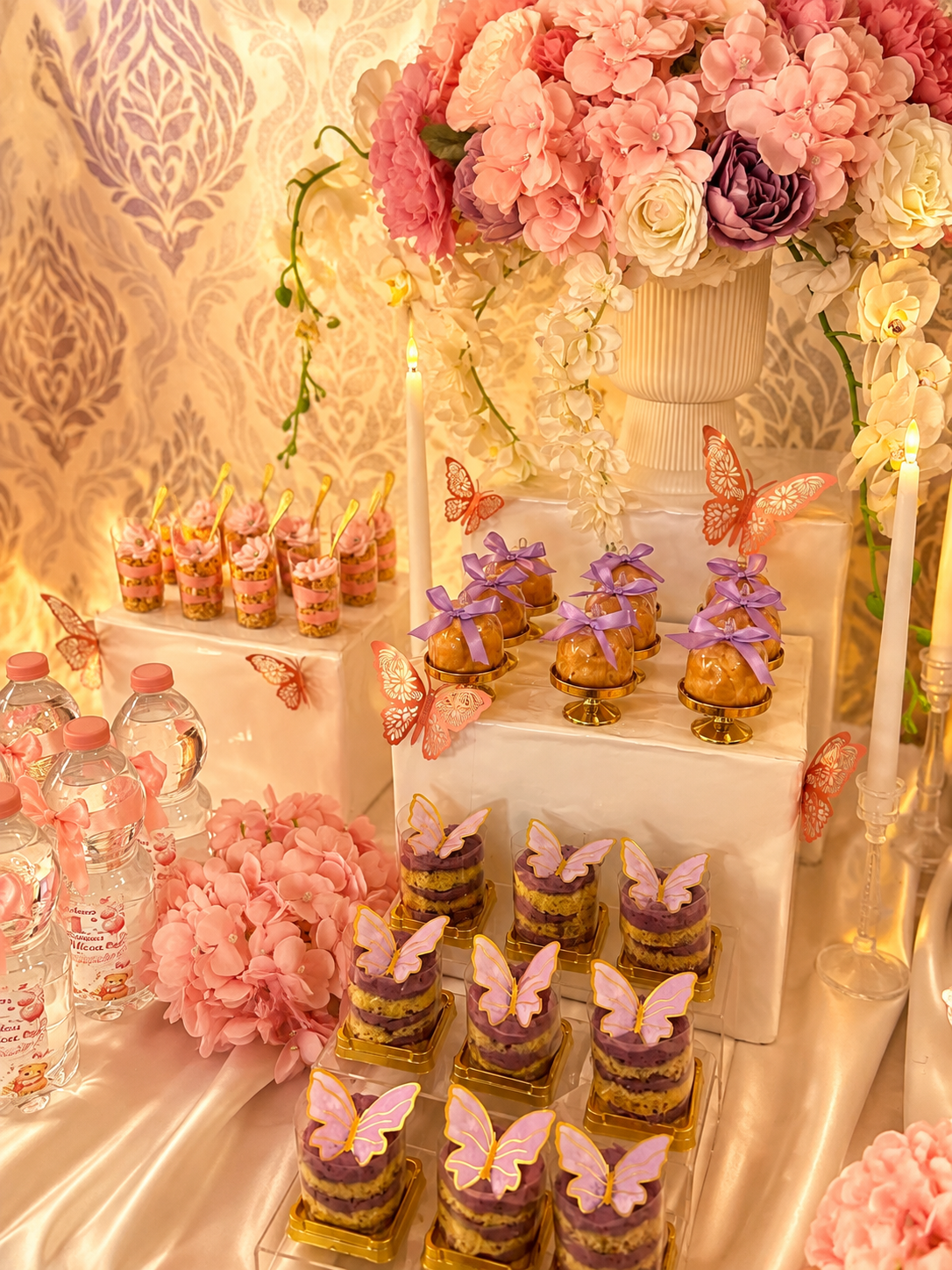 Romantische Desserttafel mit Schmetterlingsdesserts, rosa Blüten und Kerzen