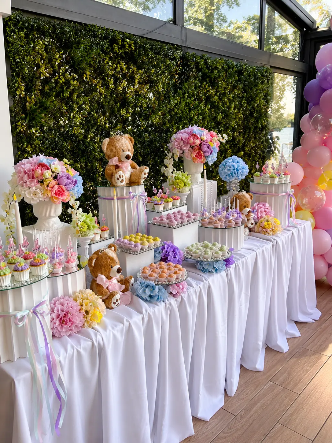 Pastellfarbene Naschereien mit Ballonbogen, Teddybären und Blumenarrangements