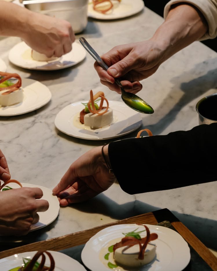 Küchenteam richtet feine Desserts mit Fruchtdekor auf Marmorplatte an