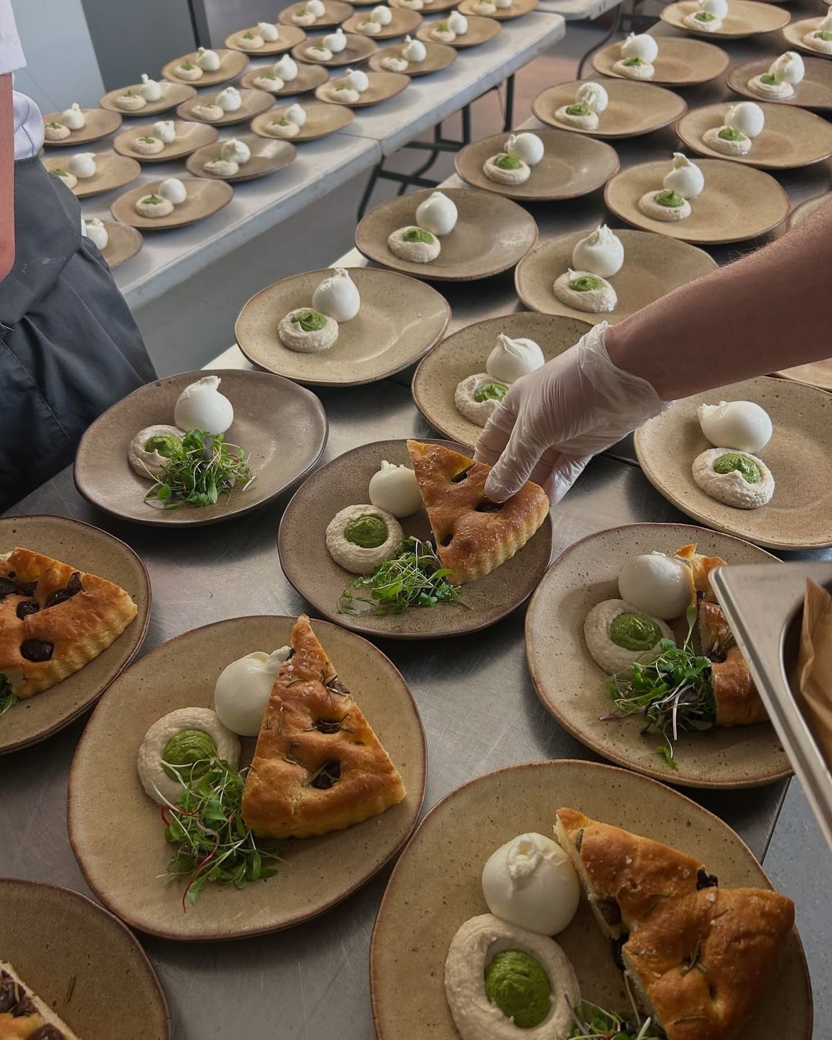 Vorbereitete Vorspeisenteller mit Focaccia, Creme und frischen Kräutern in der Lieferküche