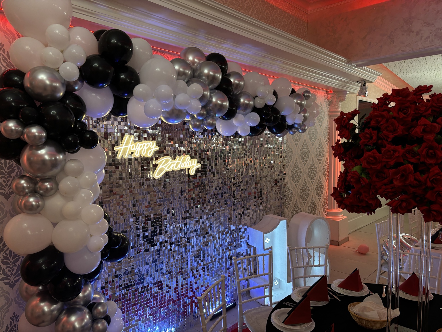 Glamouröse Geburtstagsdekoration mit schwarz-weiß-silberner Ballongirlande, Spiegelwand und roten Rosen
