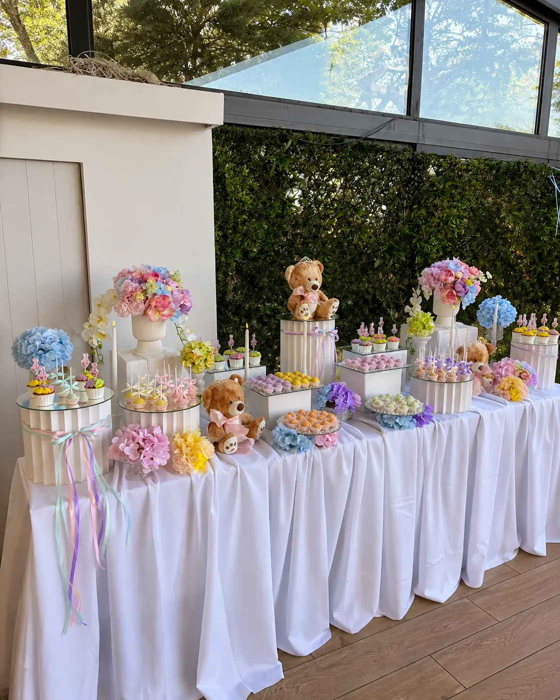 Süßigkeitentafel in Pastelltönen mit Teddybären, Blüten und Mini-Cupcakes