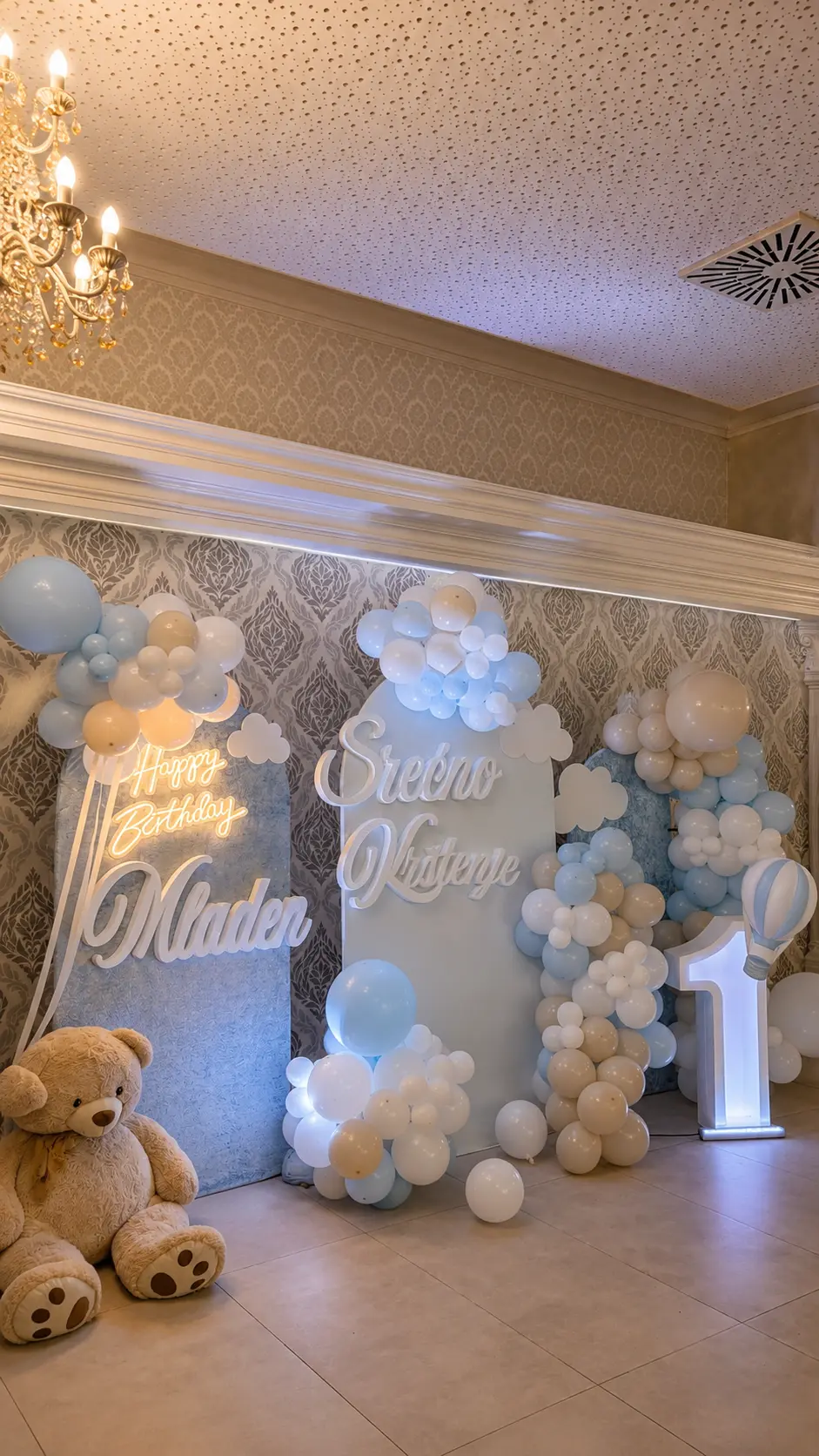 Pastell-Dekoration zur Taufe mit hellblauen und weißen Ballonwolken, Leuchtschrift, Zahl Eins und großem Teddybär